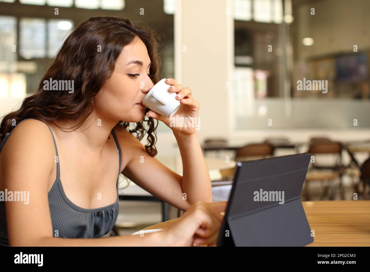 Femme buvant du café et utilisant une tablette dans un restaurant Banque D'Images