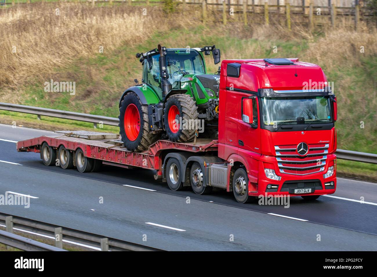 2017 Red MERCEDES BENZ 2551LS 12809cc Diesel ACTROS camion transportant un tracteur FENDT T20 sur chargeur bas ; se déplaçant sur l'autoroute M6, Royaume-Uni Banque D'Images