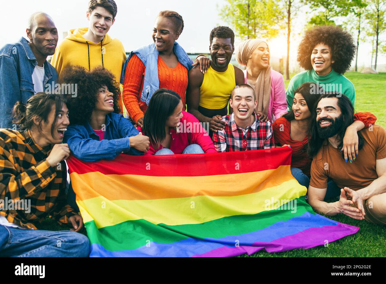 Diverses personnes ayant le plaisir de tenir le drapeau arc-en-ciel LGBT en plein air - Focus sur le visage d'homme gay Banque D'Images