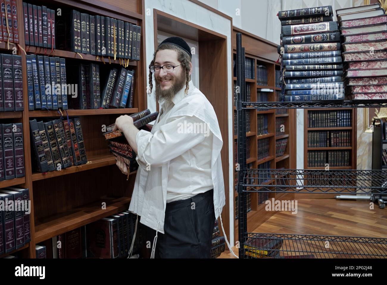 Un homme dans une synagogue enlève des volumes d'Exode et ajoute des volumes de Lévitique afin que les fidèles puissent garder la trace pendant les lectures de Torah. À New York. Banque D'Images