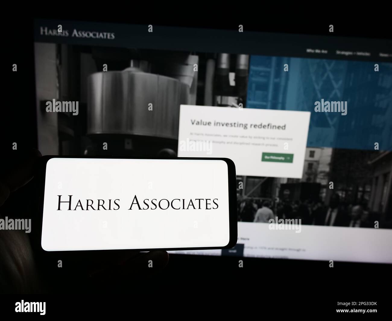 Personne détenant un smartphone avec le logo de la société d'investissement américaine Harris Associates L.P. sur l'écran devant le site Web. Mise au point sur l'affichage du téléphone. Banque D'Images