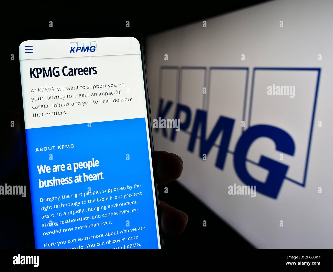 Personne tenant un téléphone portable avec la page Web de la société de services professionnels KPMG à l'écran devant le logo. Concentrez-vous sur le centre de l'écran du téléphone. Banque D'Images
