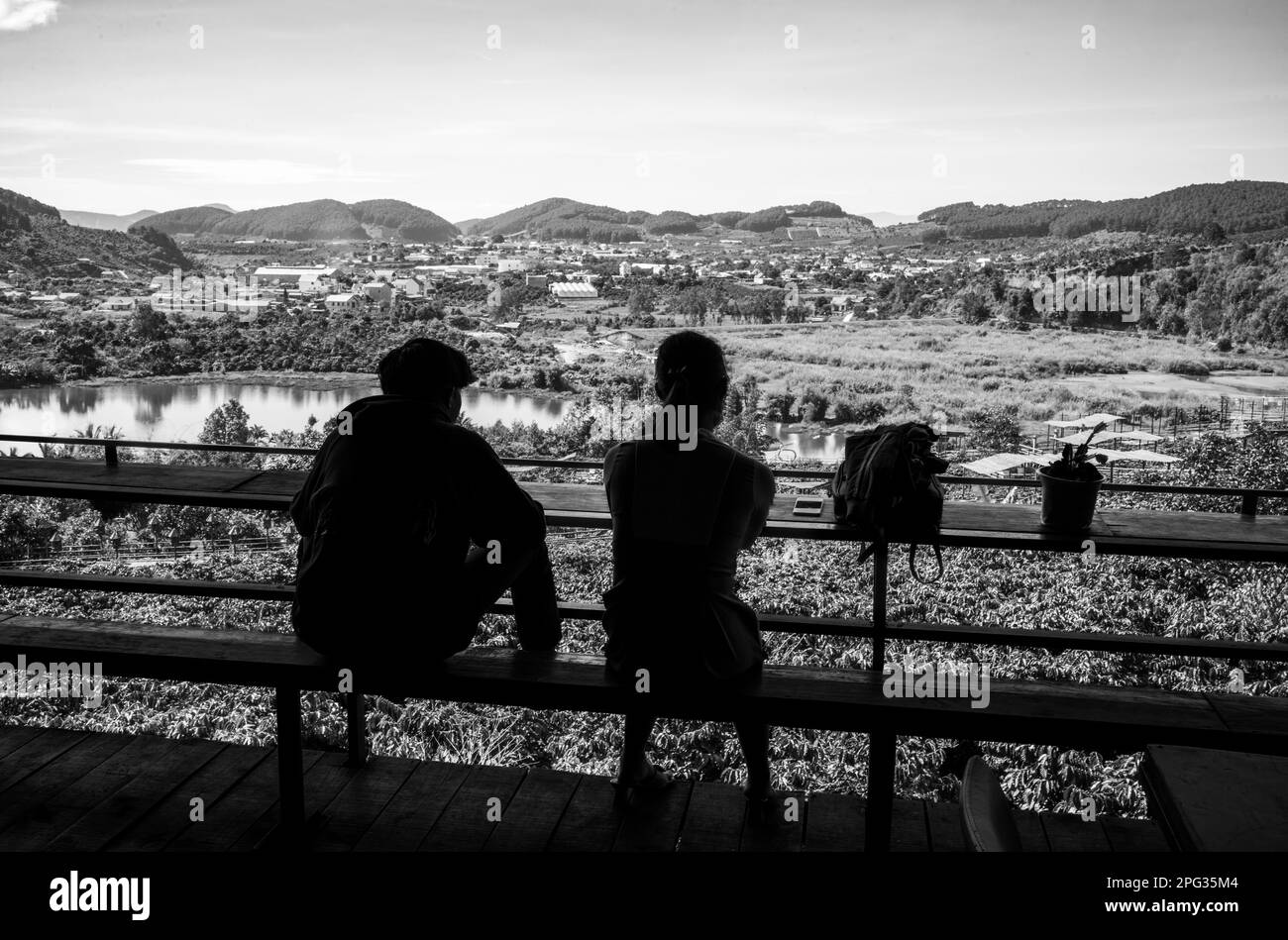Un jeune couple vietnamien s'assoit au café-jardin me Linh et regarde à travers les caféiers, le lac DAP Cam Ly et une vallée dans les hautes terres centrales nea Banque D'Images