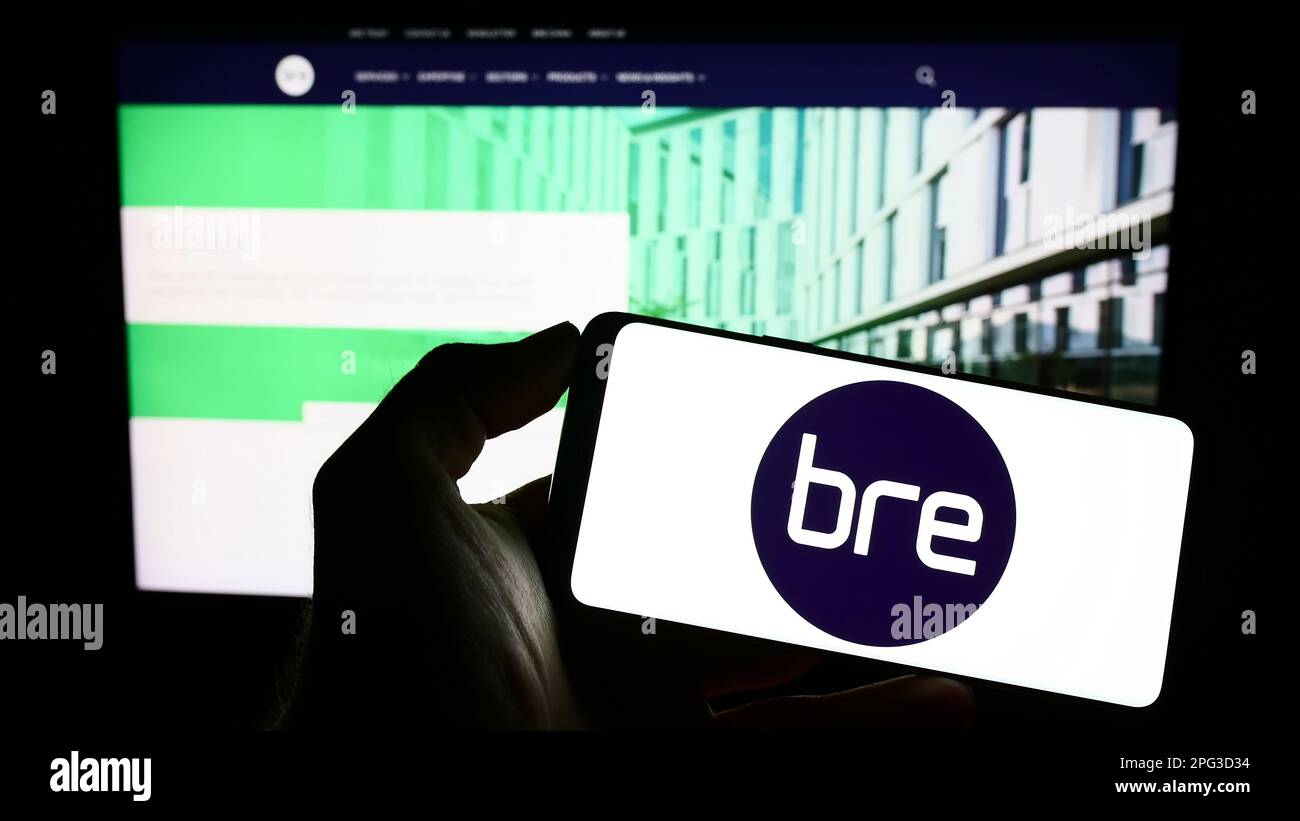 Personne tenant un téléphone portable avec le logo de Building Research Centre (BRE) à l'écran en face de la page Web. Mise au point sur l'affichage du téléphone. Banque D'Images