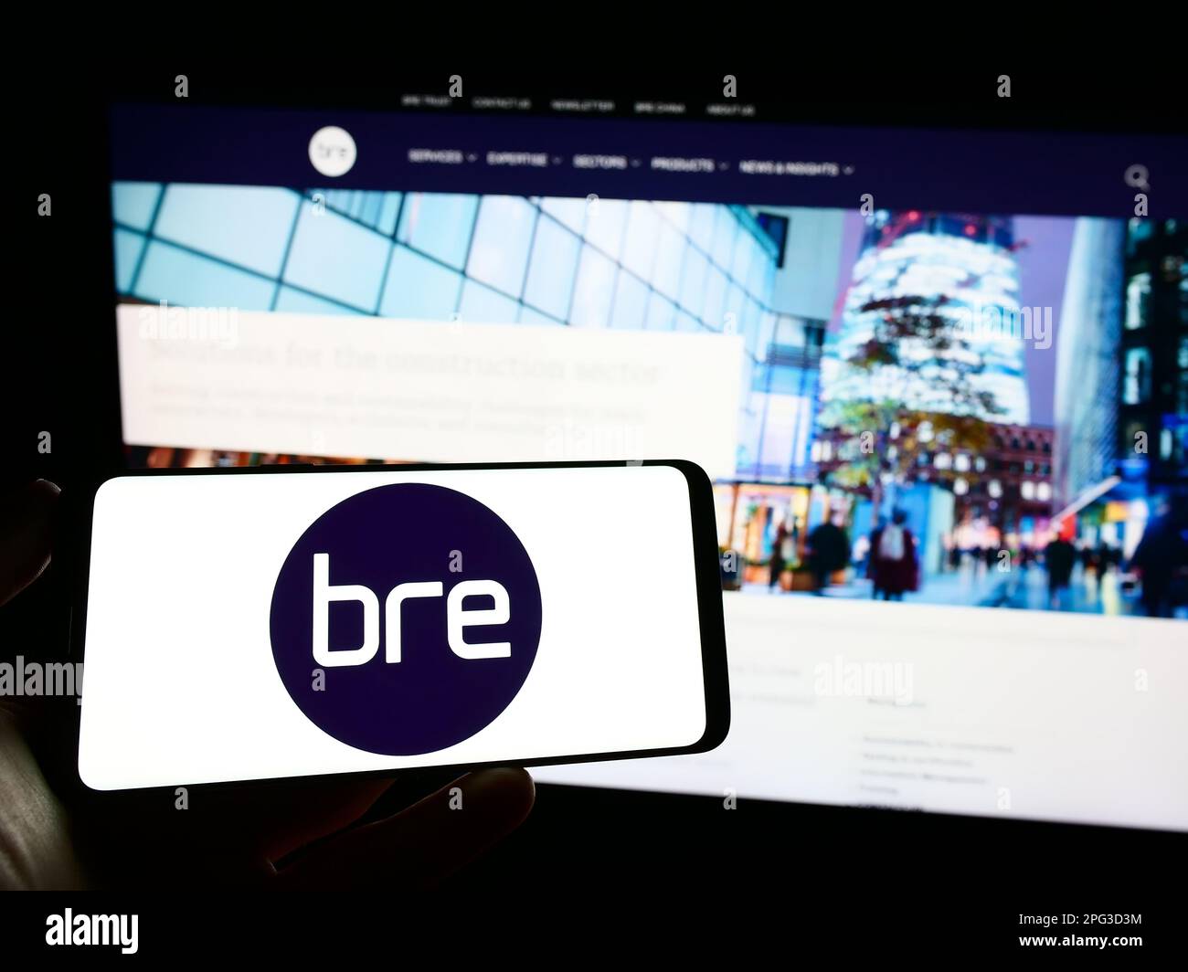 Personne tenant un téléphone portable avec le logo de Building Research Centre (BRE) à l'écran devant la page Web. Mise au point sur l'affichage du téléphone. Banque D'Images