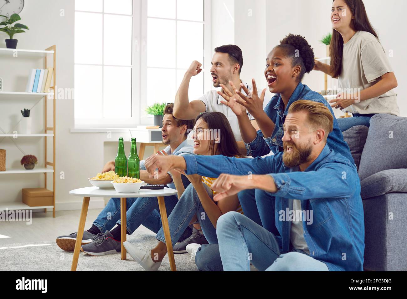 De joyeux amis multiraciaux qui applaudissent tout en regardant le football à la télévision Banque D'Images