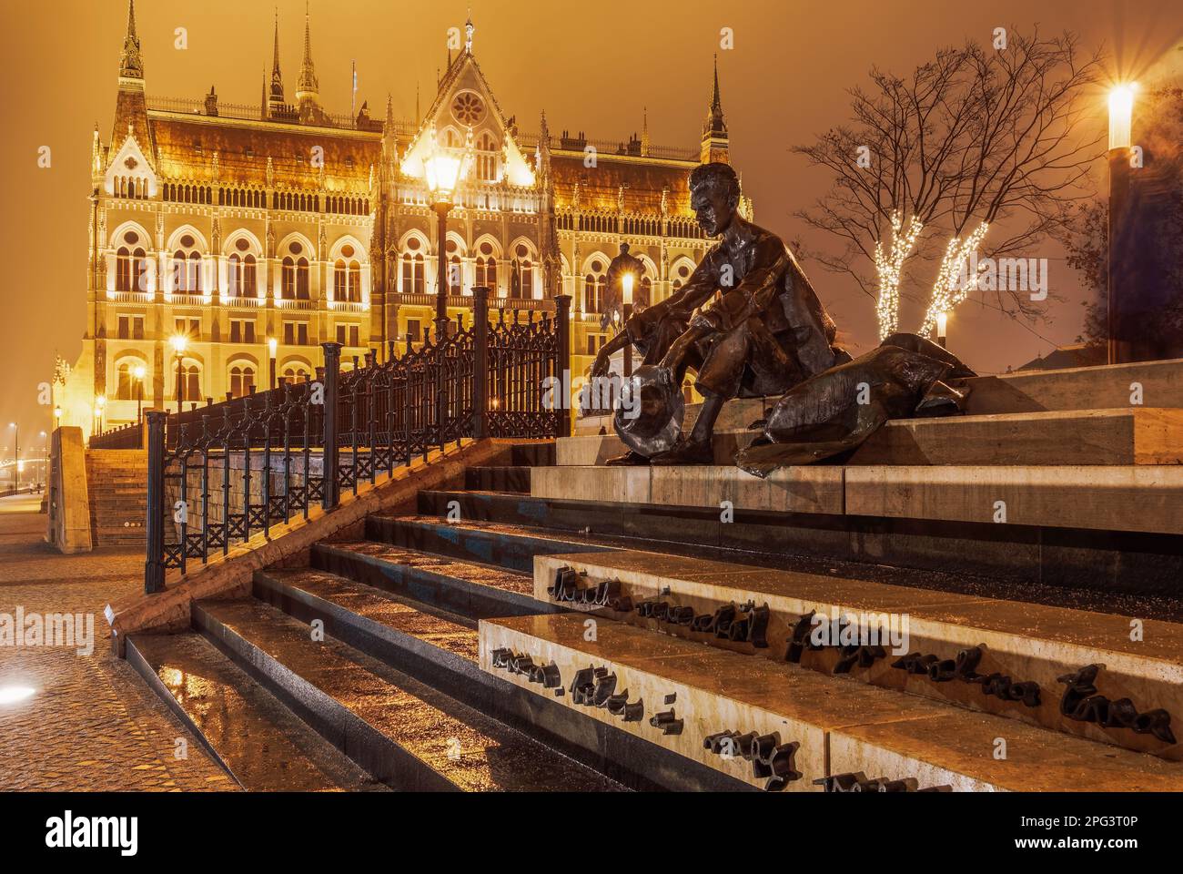 Budapest, Hongrie vue nocturne du célèbre poète Attila Jozsef statue de bronze avant le bâtiment illuminé de style gothique du Parlement hongrois. Banque D'Images