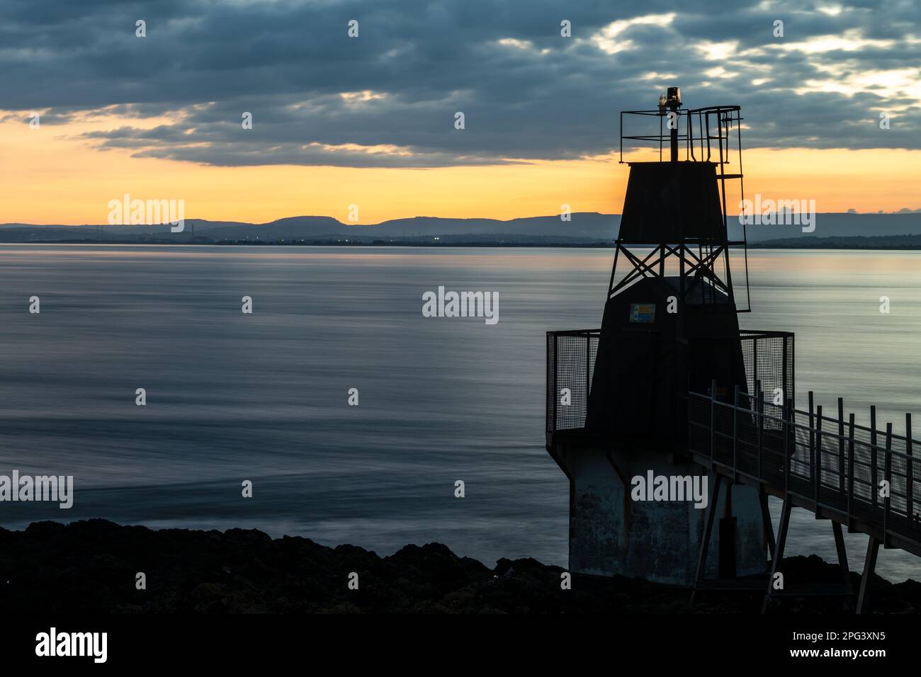 Le soleil se couche sur le phare de Battery point à Portisead sur le canal de Bristol, avec les collines du sud du pays de Galles derrière. Banque D'Images