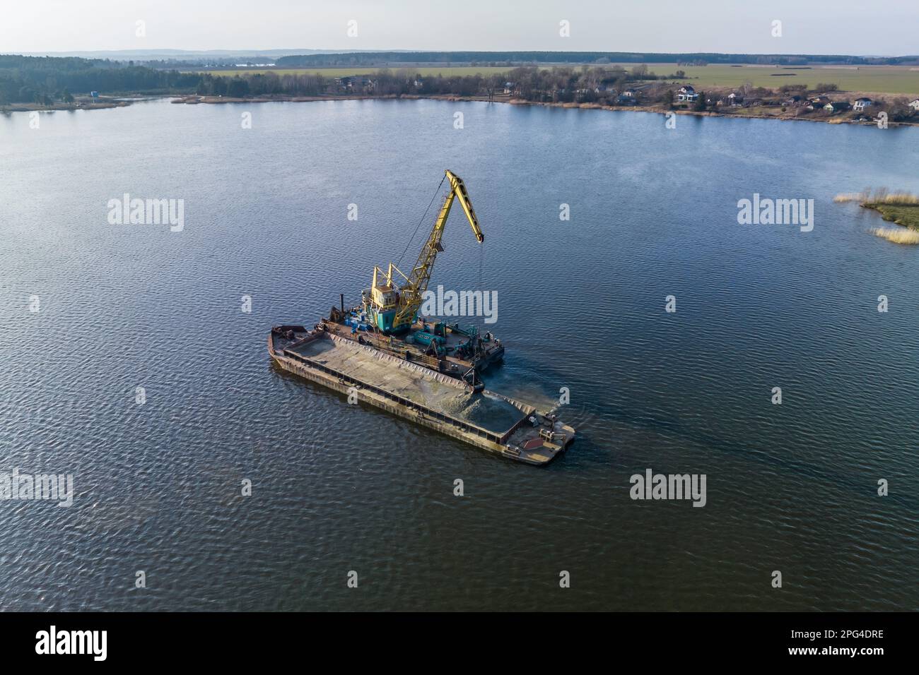 vue aérienne sur la grue extrait les minéraux du fond sur une immense barge au milieu du lac ou de la mer Banque D'Images