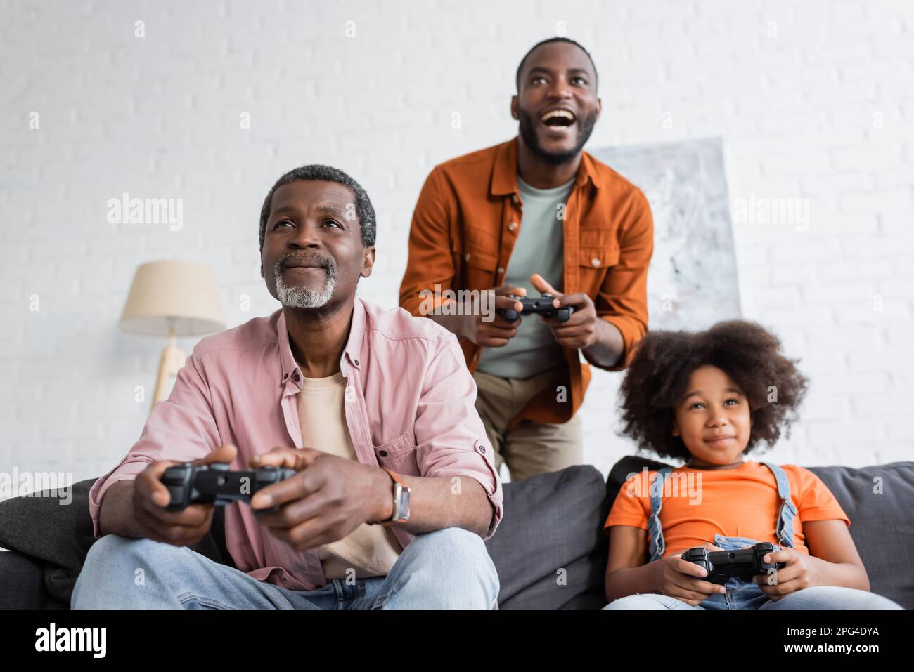 KIEV, UKRAINE - 17 JUILLET 2021: Grand-père afro-américain jouant au jeu vidéo avec la famille à la maison Banque D'Images