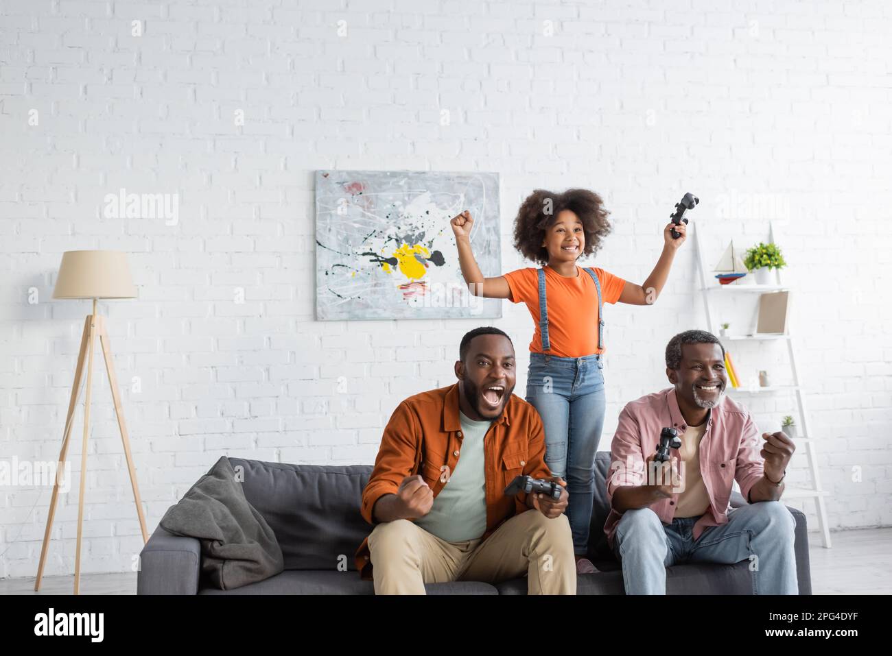 KIEV, UKRAINE - 17 JUILLET 2021 : une famille afro-américaine excitée jouant au jeu vidéo dans le salon Banque D'Images