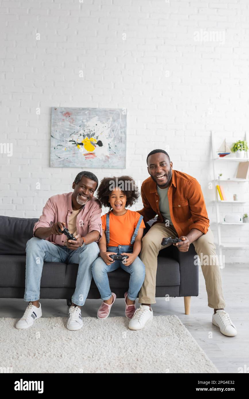 KIEV, UKRAINE - 17 JUILLET 2021: Joyeux afro-américains hommes et enfants jouant au jeu vidéo à la maison Banque D'Images