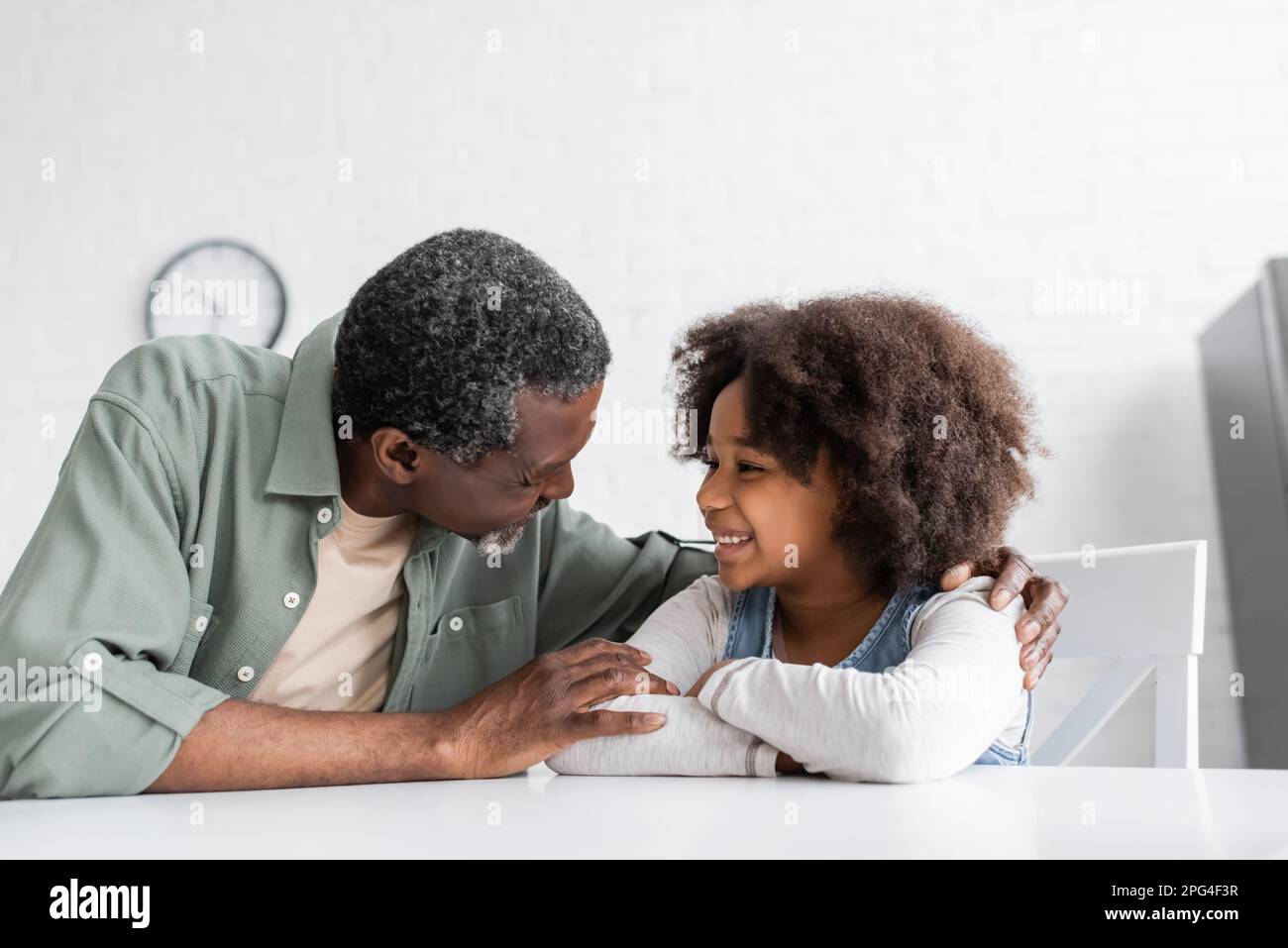 joyeux grand-père afro-américain embrassant la petite-fille en cuisine, image de stock Banque D'Images