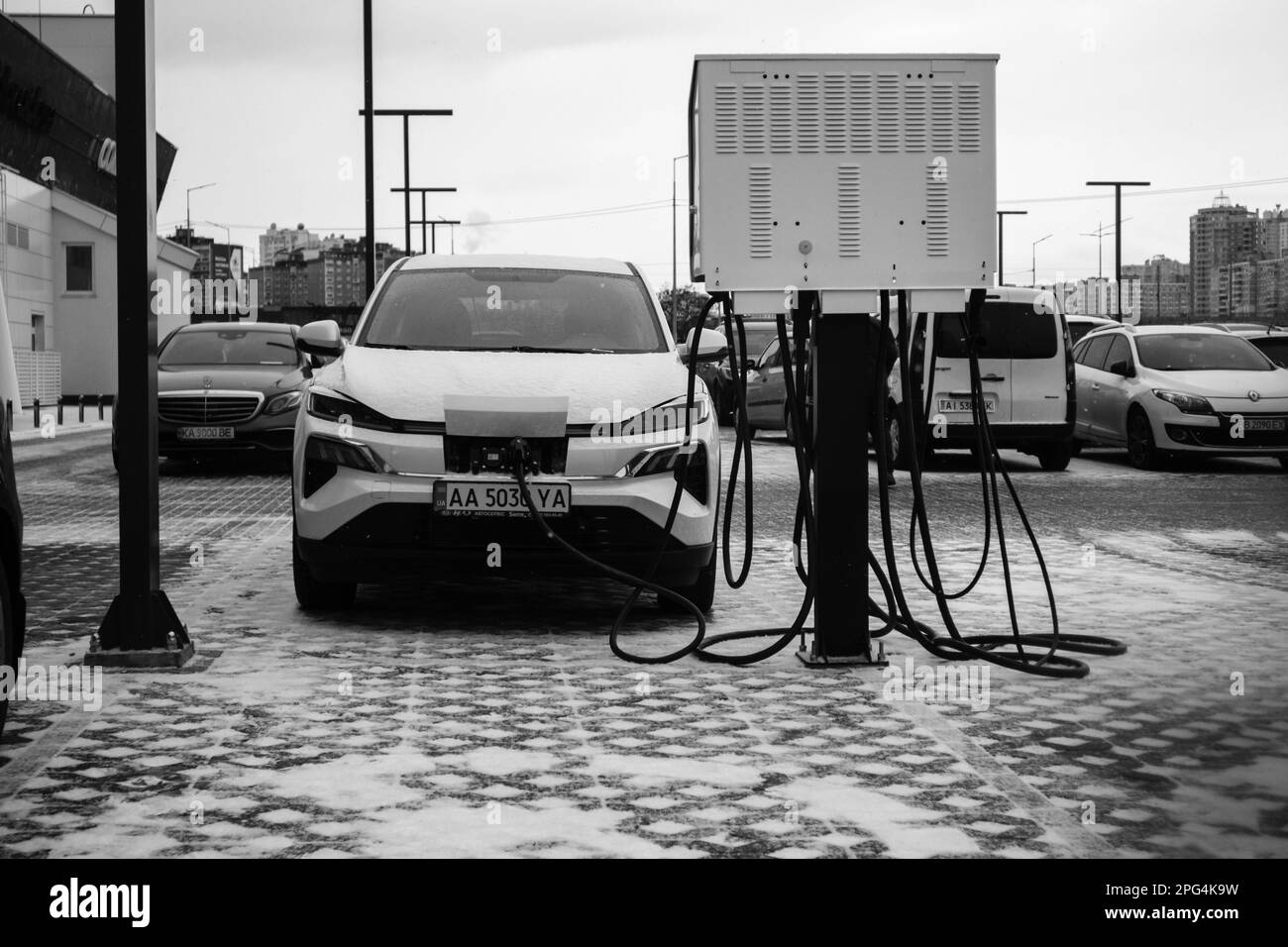 Kiev, Ukraine 2 février 2023 Une voiture électrique blanche est chargée à une centrale électrique. Transport écologique à la station de remplissage électrique en hiver Un parking Banque D'Images