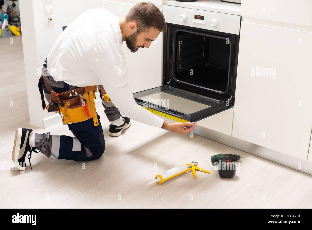 réparateur examinant un four avec un tournevis dans la cuisine avec une  mallette à outils Photo Stock - Alamy