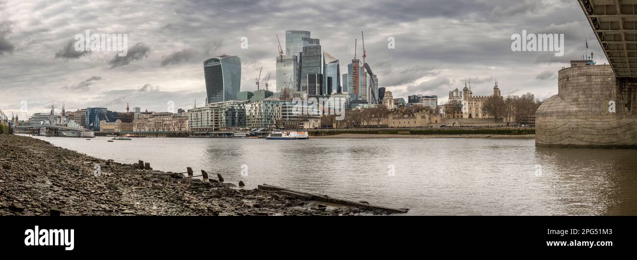 Vue sur le HMS Belfast prise sous le Tower Bridge à marée basse sur la Tamise. Sur la rive opposée le nouveau développement de la construction de verre Banque D'Images