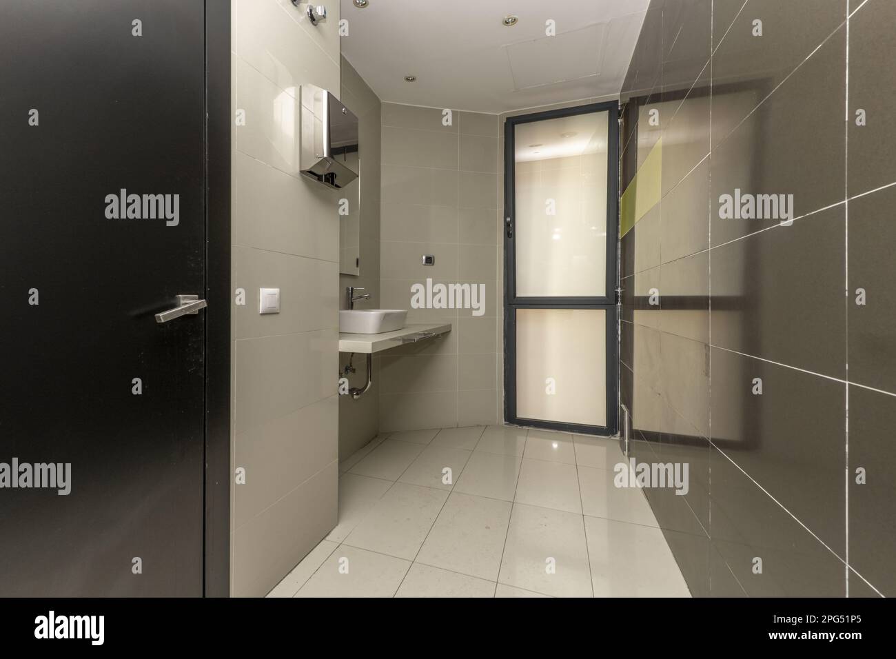 Une toilette de bureau avec évier, un comptoir semblable en marbre, des miroirs et une fenêtre pleine hauteur Banque D'Images