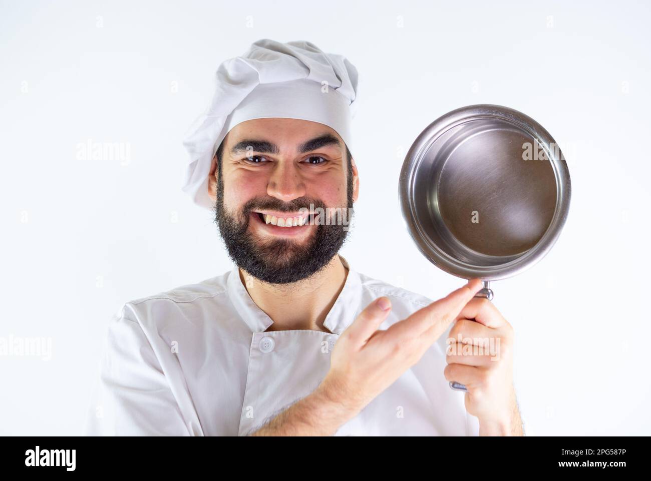 Jeune chef masculin montrant une casserole en acier inoxydable tout en souriant et en regardant l'appareil photo. Isolé sur un fond blanc Banque D'Images