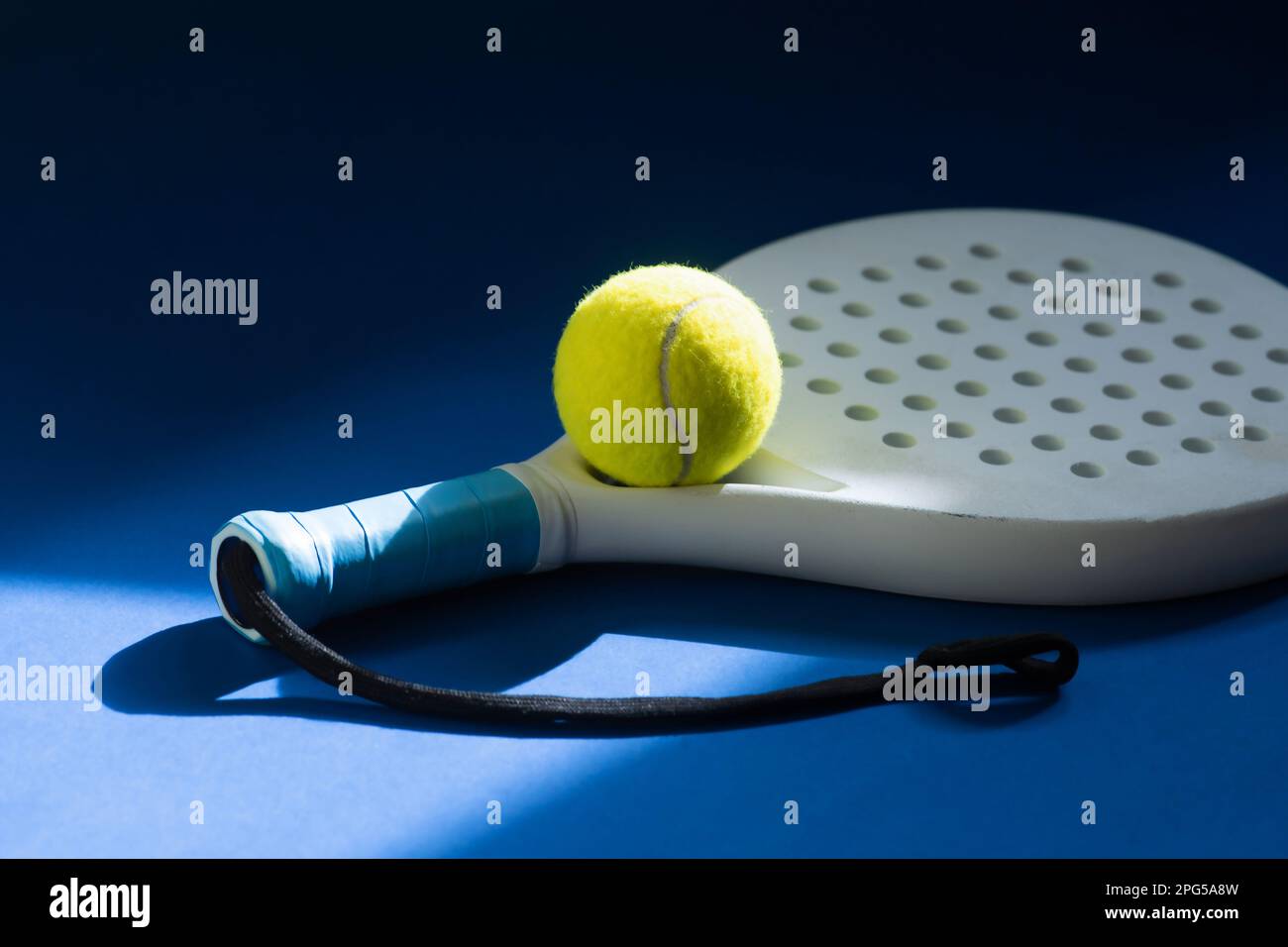 Raquette de paddle-tennis professionnelle blanche et balle jaune avec éclairage naturel sur fond bleu. Affiche horizontale sur le thème du sport, cartes de vœux, tête Banque D'Images