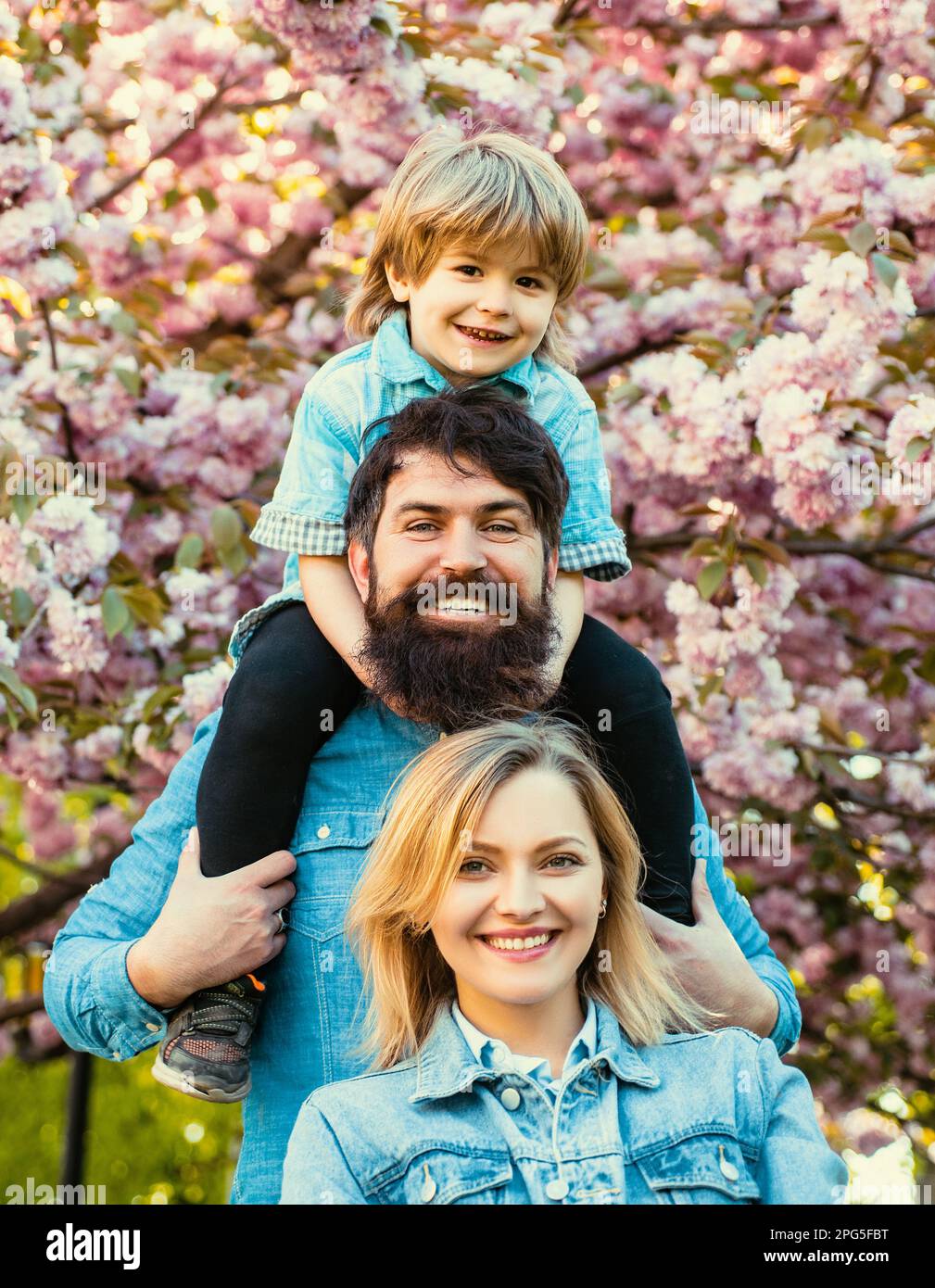 Mère, père et fils. Belle famille appréciant dans un parc de fleurs de printemps. Petit fils