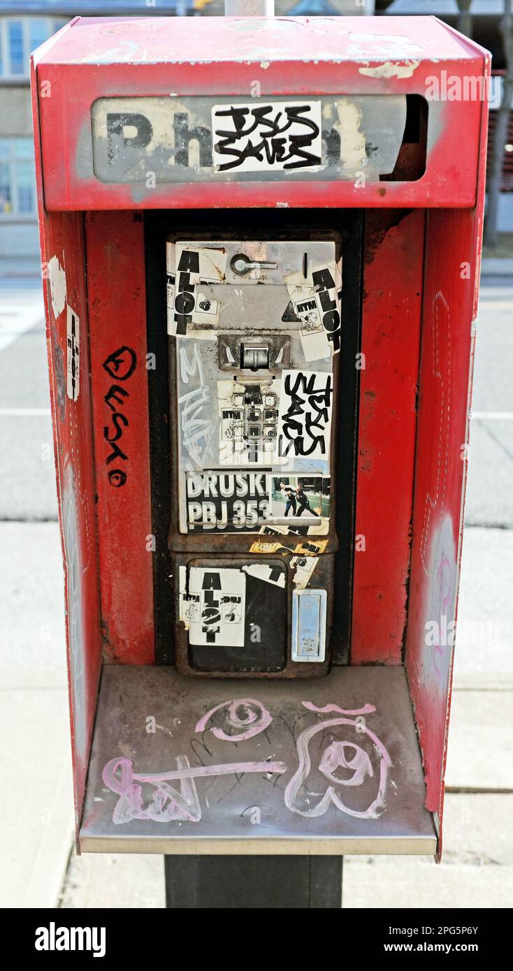 Un vieux téléphone public rouge lourdement endommagé par les graffitis et le vandalisme n'a pas encore de récepteur est encore attaché au poteau à Cleveland, Ohio, USA. Banque D'Images