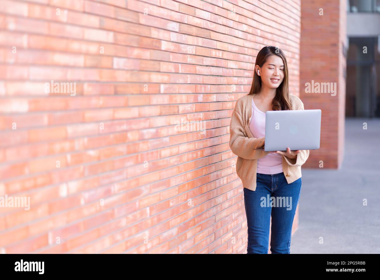 Étudiante asiatique étudiant pour des examens dans le domaine de l'université. Communiquer via un téléphone portable ou un ordinateur portable connecté à Internet. avec beaucoup de sou Banque D'Images