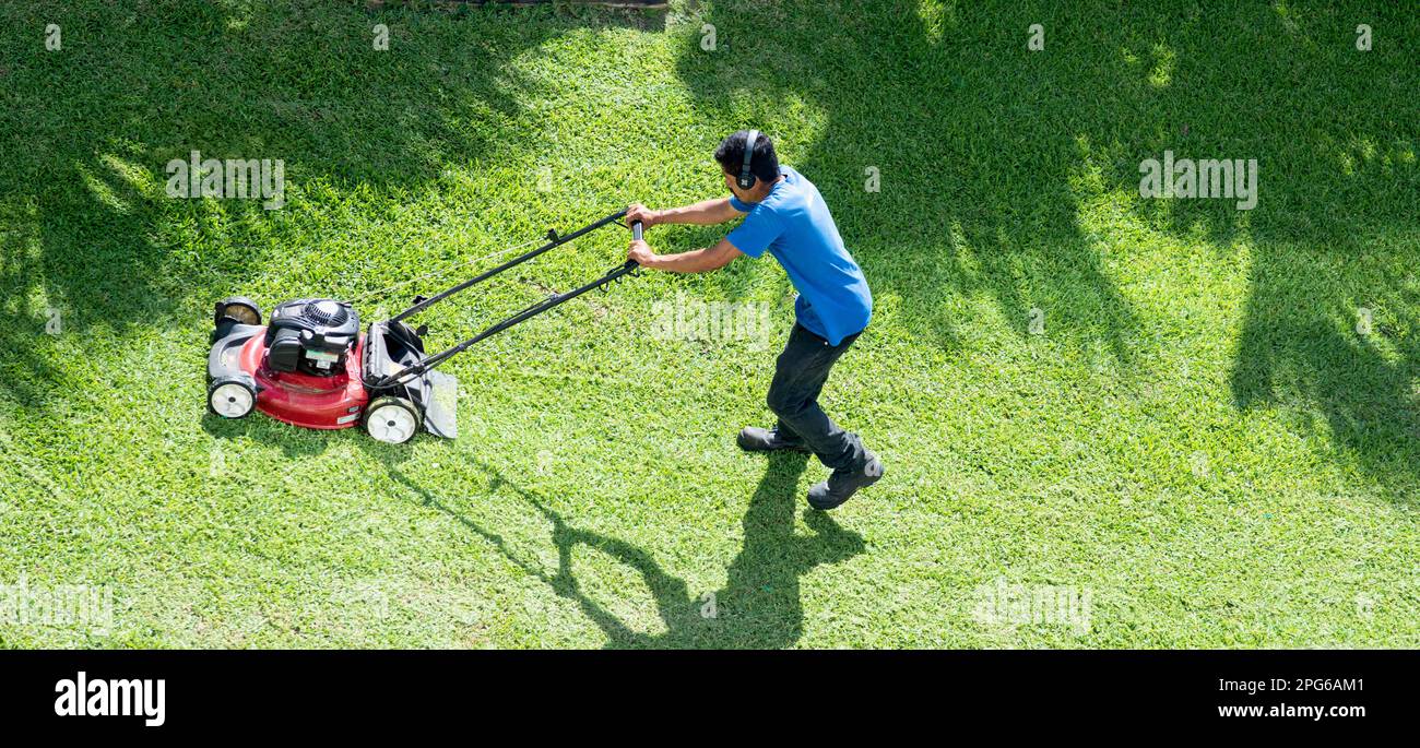 Jardinier mexicain fauchant la pelouse avec une tondeuse électrique, vue d'en haut Banque D'Images