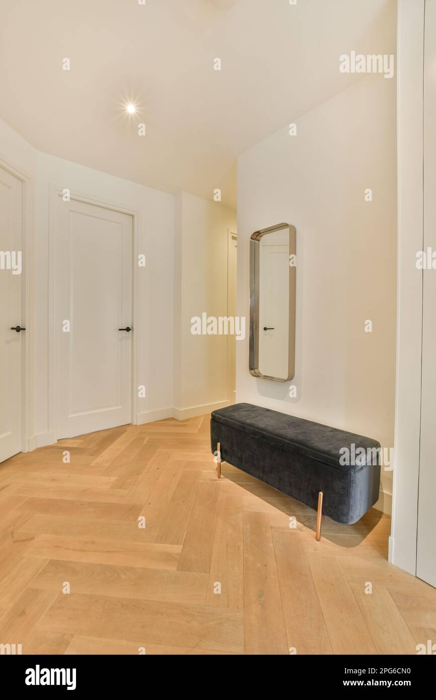 un salon avec parquet et murs blancs, dont un banc en velours noir au centre de la pièce Banque D'Images