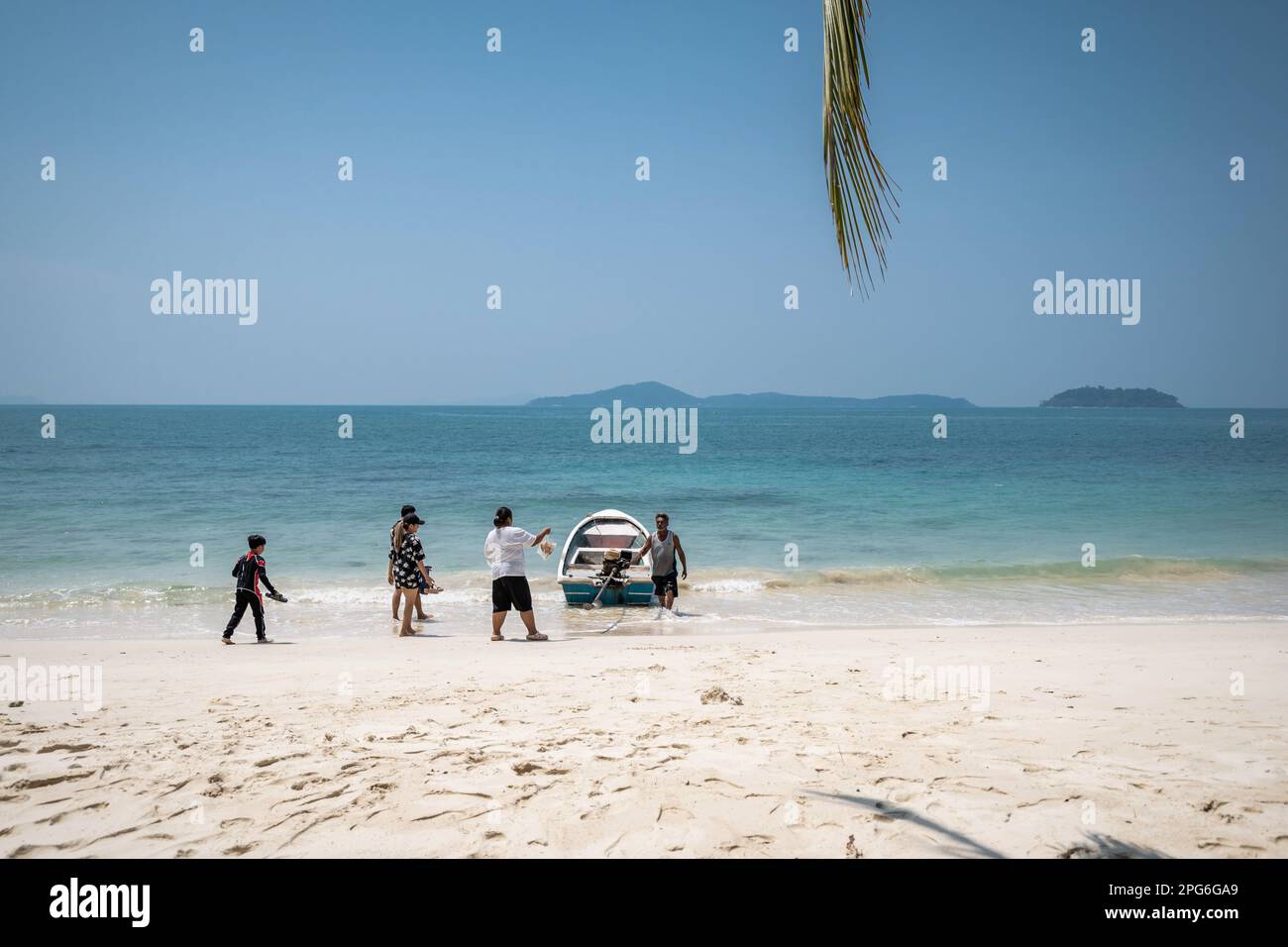 Une famille touristique embarque pour une visite privée avec un bateau de pêche local à long Beach, un long chemin sur la côte est de Ko Changís à cette étroite plage, vraiment loin de tous pas de lieux touristiques de l'île. La vie quotidienne sur Koh Chang, l'une des plus grandes îles de Thaïlande, le pays équilibre la durabilité avec le retour du tourisme de masse, une composante essentielle du développement économique de la Thaïlande. Banque D'Images