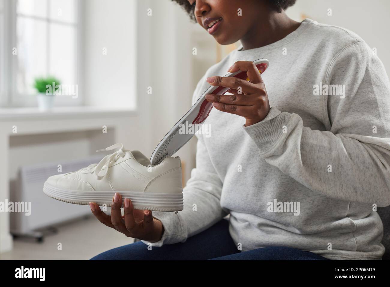 Femme afro-américaine mettant une semelle intérieure orthopédique dans la  chaussure Photo Stock - Alamy