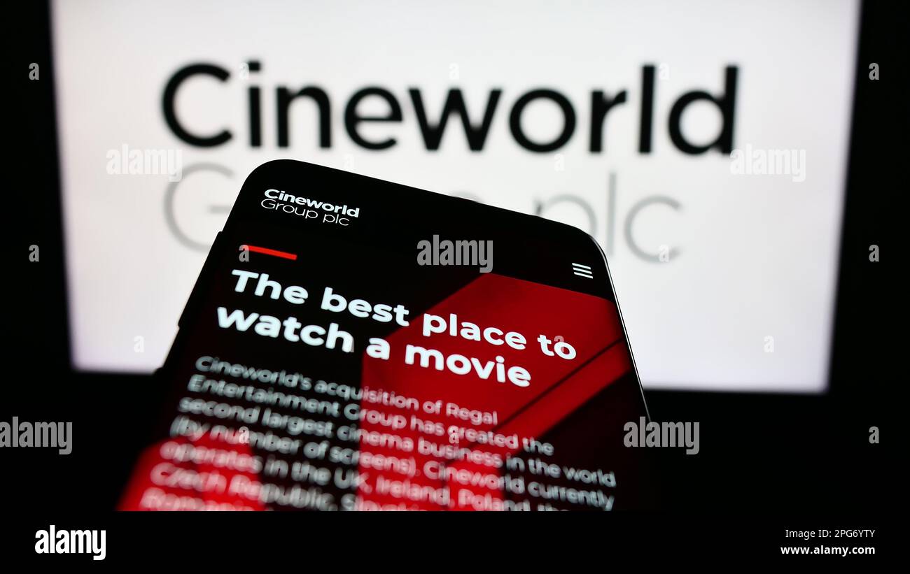 Téléphone mobile avec le site Web de la société britannique de cinéma Cineworld Group plc à l'écran devant le logo de l'entreprise. Faites la mise au point dans le coin supérieur gauche de l'écran du téléphone. Banque D'Images