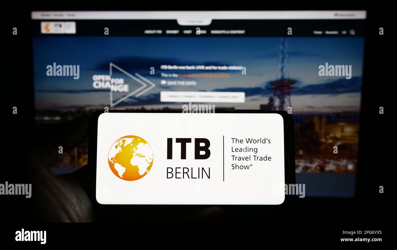 Personne tenant un téléphone portable avec le logo du salon du tourisme allemand ITB Berlin à l'écran en face de la page web. Mise au point sur l'affichage du téléphone. Banque D'Images