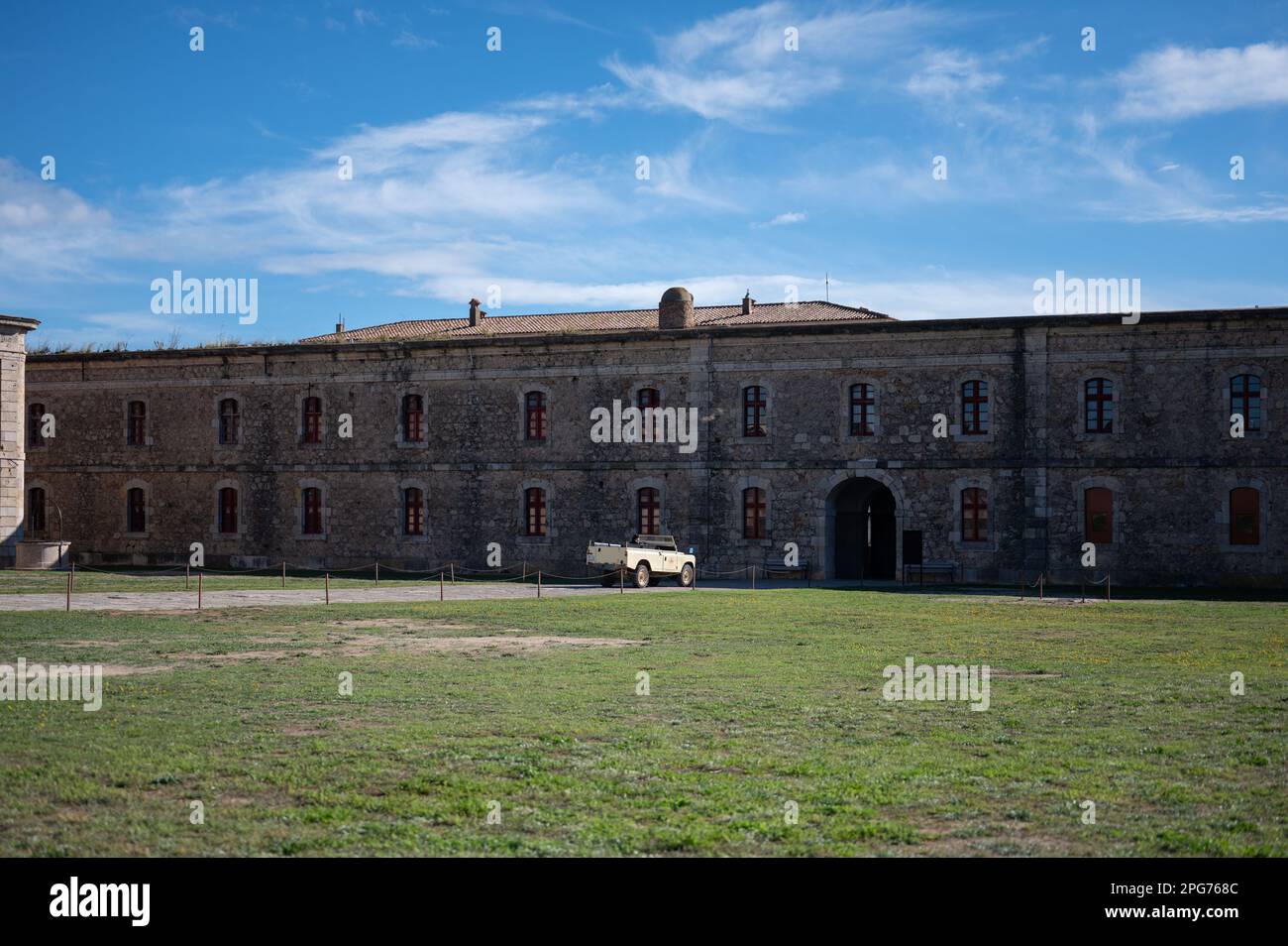 Troupeau de vaches errant dans le champ herbacé devant un bâtiment historique de la prison, avec un ciel bleu clair en arrière-plan Banque D'Images