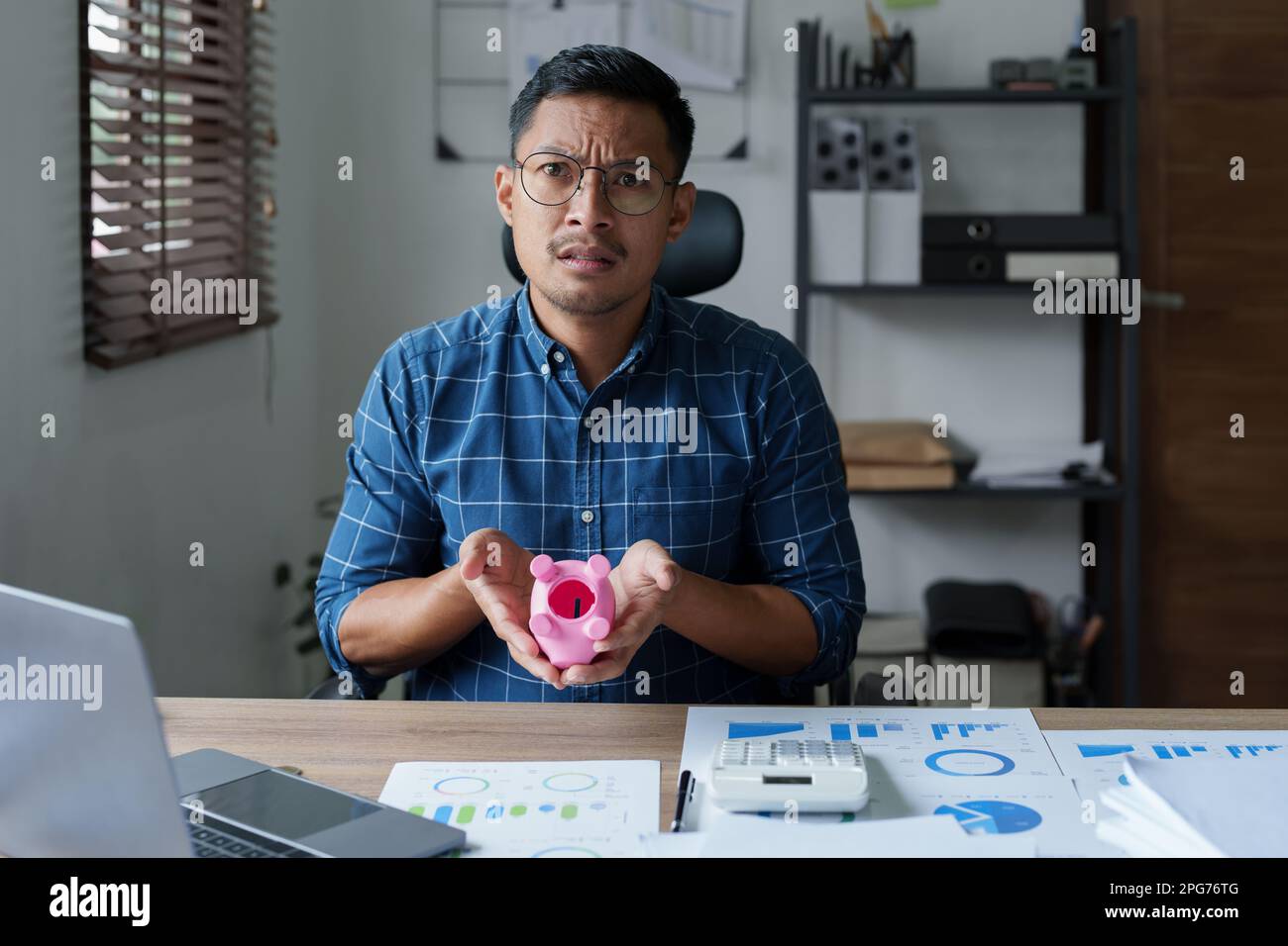 Portrait d'un homme d'affaires asiatique montrant une expression sérieuse et anxieuse dans une entreprise de PME , mais pas d'argent dans la banque de porc rose , l'épargne Banque D'Images