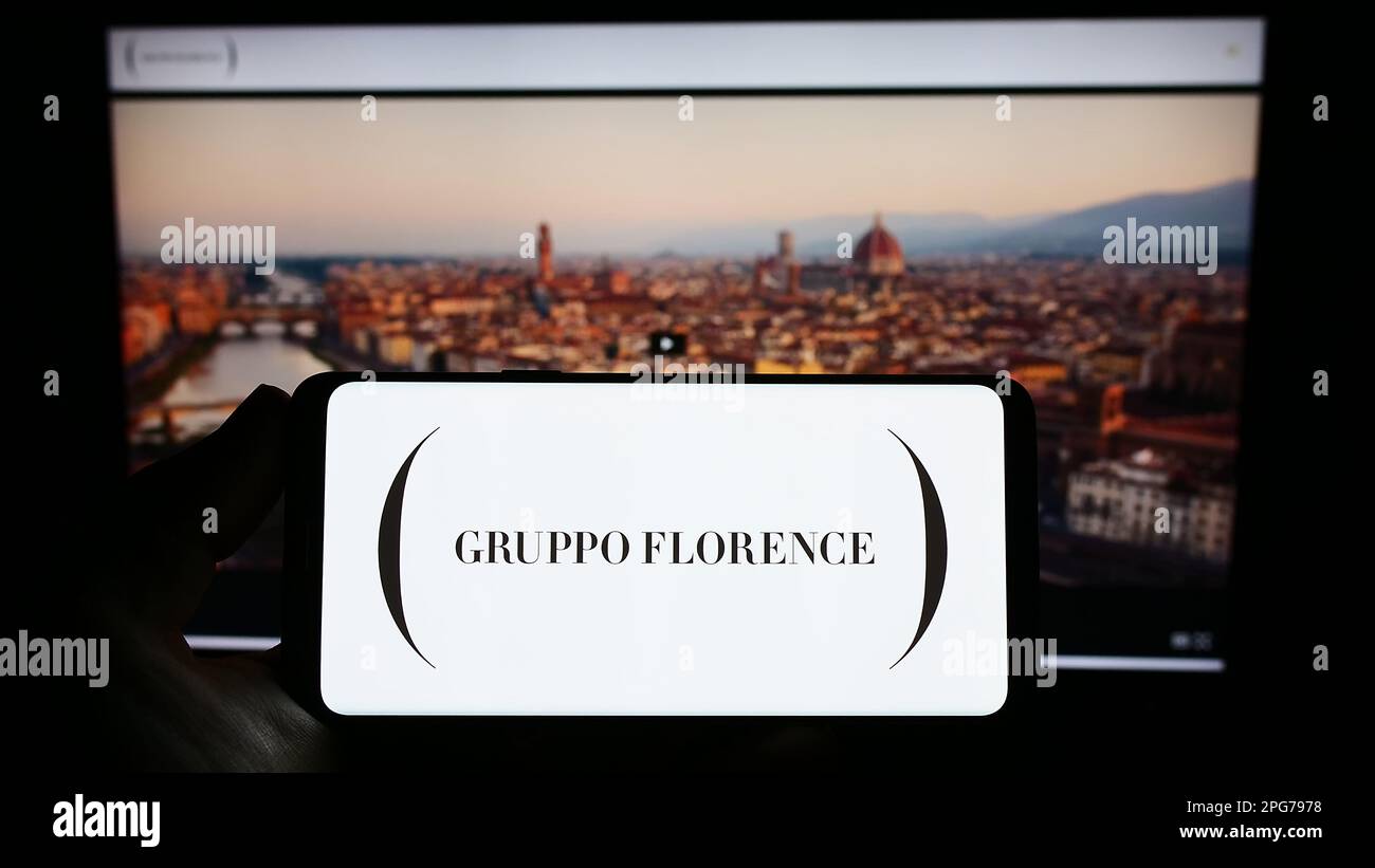 Personne tenant un smartphone avec le logo de la société italienne de mode Gruppo Florence S.p.A. à l'écran devant le site. Mise au point sur l'affichage du téléphone. Banque D'Images