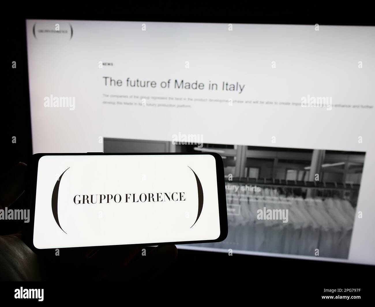 Personne tenant un téléphone portable avec le logo de la société italienne de mode Gruppo Florence S.p.A. à l'écran en face de la page web. Mise au point sur l'affichage du téléphone. Banque D'Images