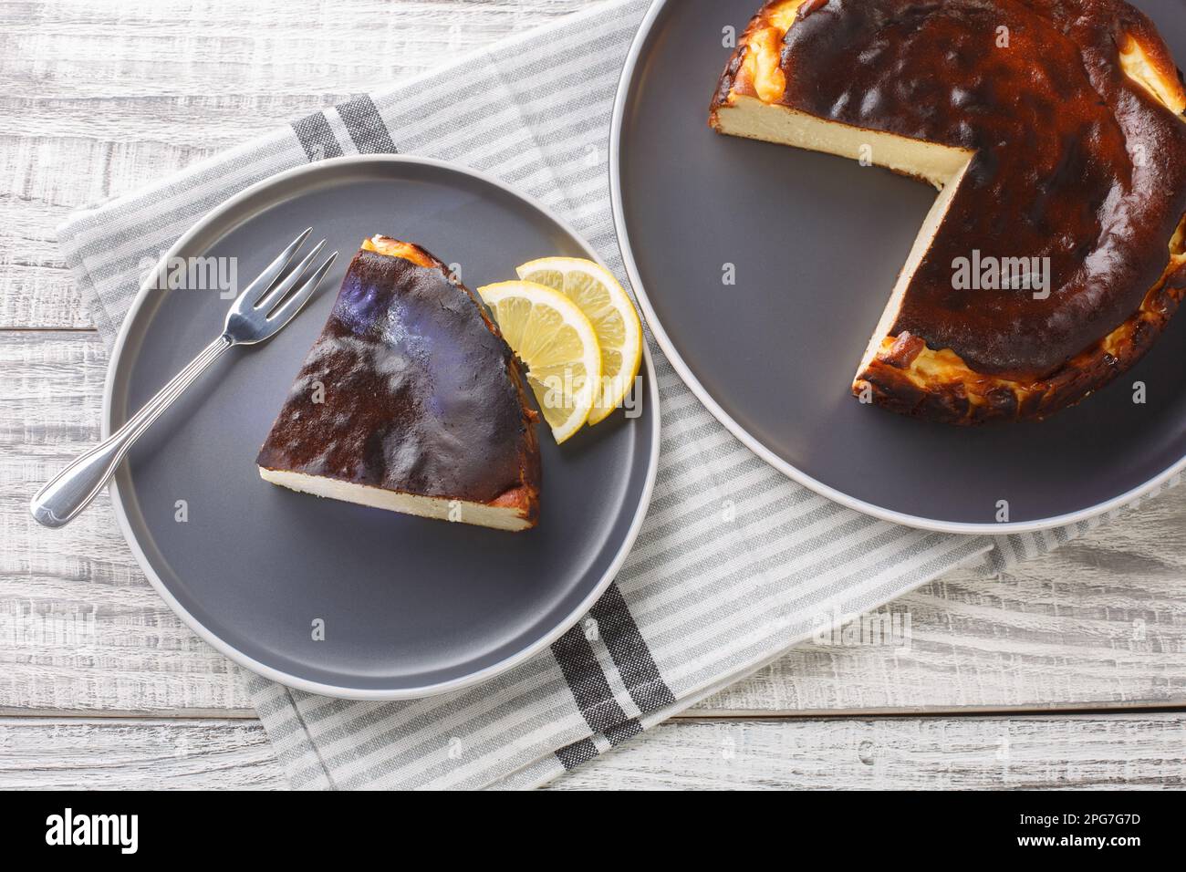 Cheesecake basque avec un centre crémeux et une croûte profondément caramélisée sur le dessus et le fond de la plaque sur la table. Vue horizontale du dessus Banque D'Images