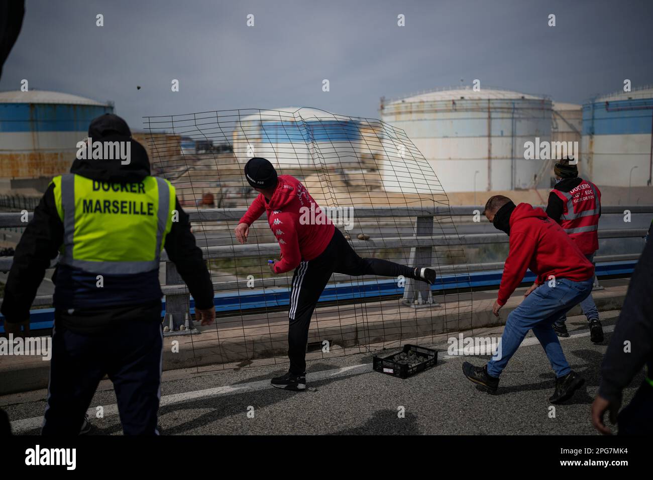 Oil workers throw stones against riot police as they block the access