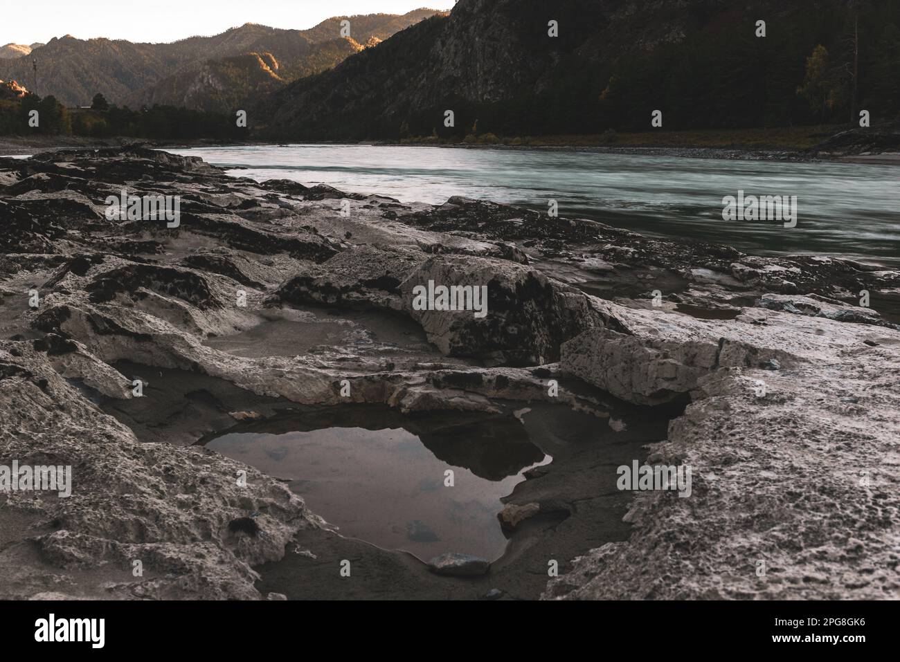 Les renfoncements dans une pierre de différentes roches sont remplis d'eau sur la rive de la rivière de montagne Katun près d'un rocher dans Altai au coucher du soleil à l'ombre dedans Banque D'Images