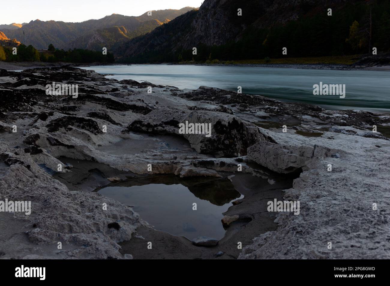 Les renfoncements dans une pierre de différentes roches sont remplis d'eau avec réflexion sur la rive de la rivière de montagne Katun près d'un rocher dans Altai au coucher du soleil Banque D'Images