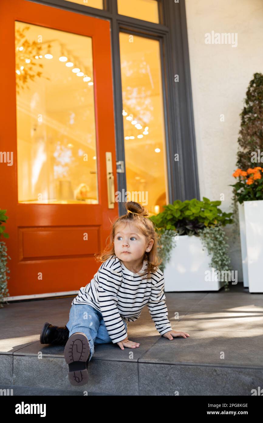 Bébé fille en chemise à manches longues et jeans assis à côté de la maison  à Miami, image de stock Photo Stock - Alamy