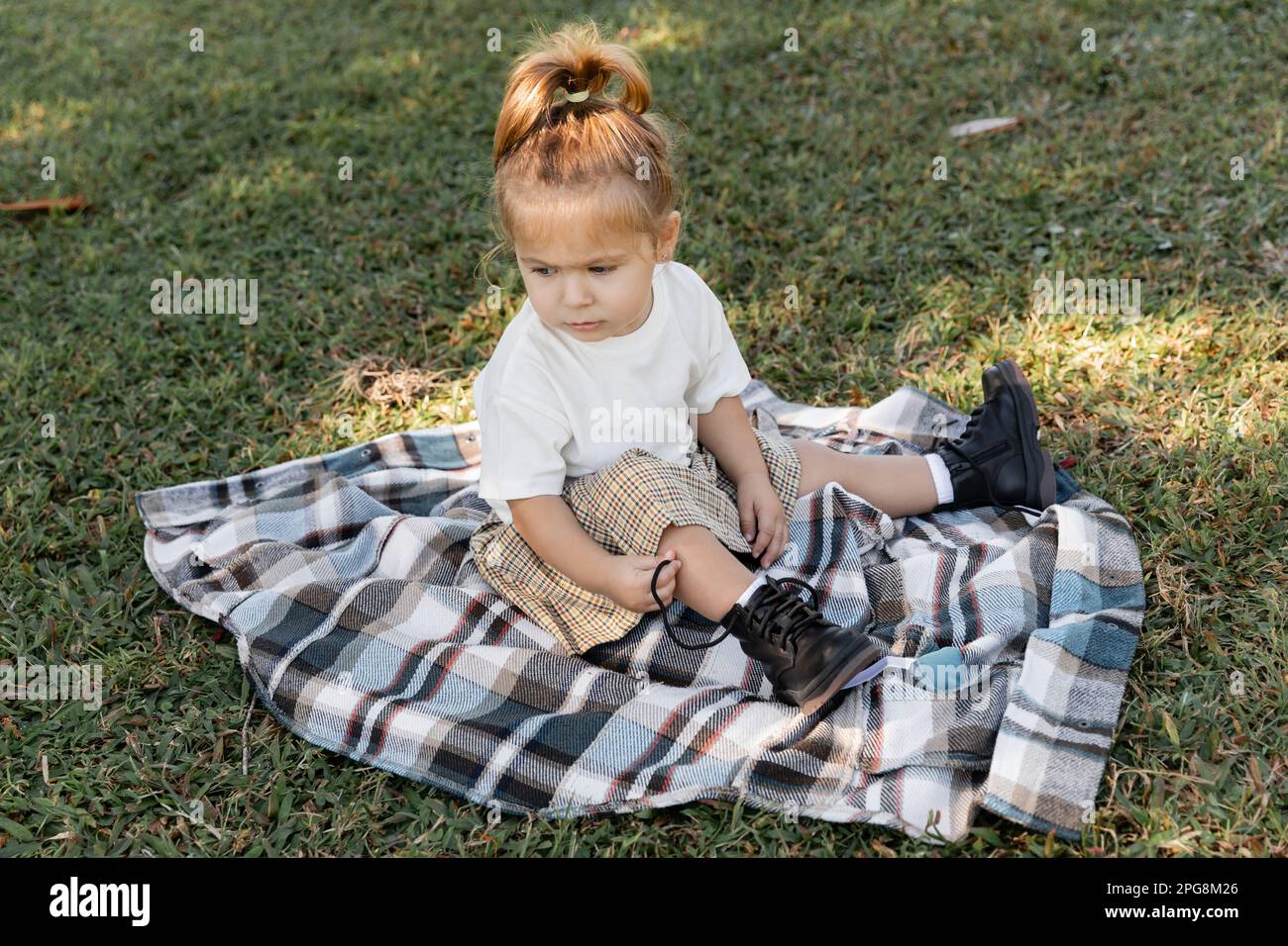 bébé fille en jupe à carreaux et bottes assis sur une couverture pendant le  pique-nique, image de stock Photo Stock - Alamy