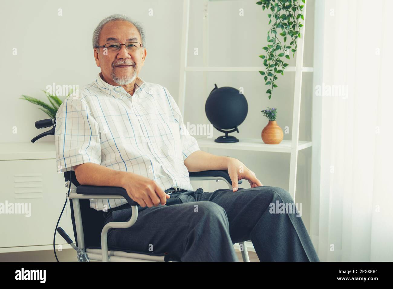 Portrait d'un homme âgé dans un fauteuil roulant seul avec lui-même à la  maison mais content de son lot dans la vie. Installation de convalescence  pour les personnes paralysées Photo Stock -