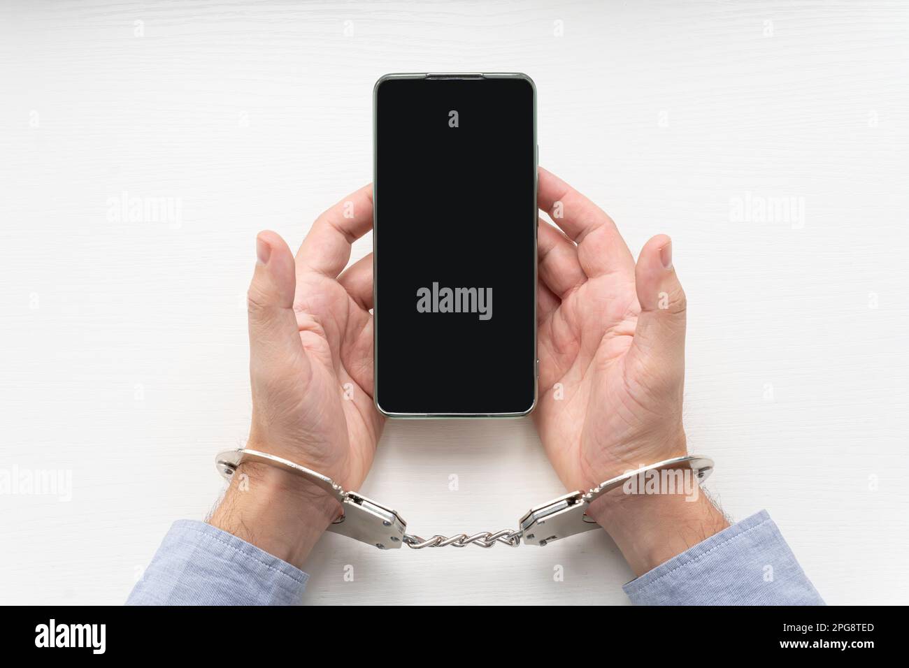 Menottes et téléphone mobile sur la clôture de la table blanche en bois. droit d'appel lorsqu'il est arrêté ou détenu par la police Banque D'Images