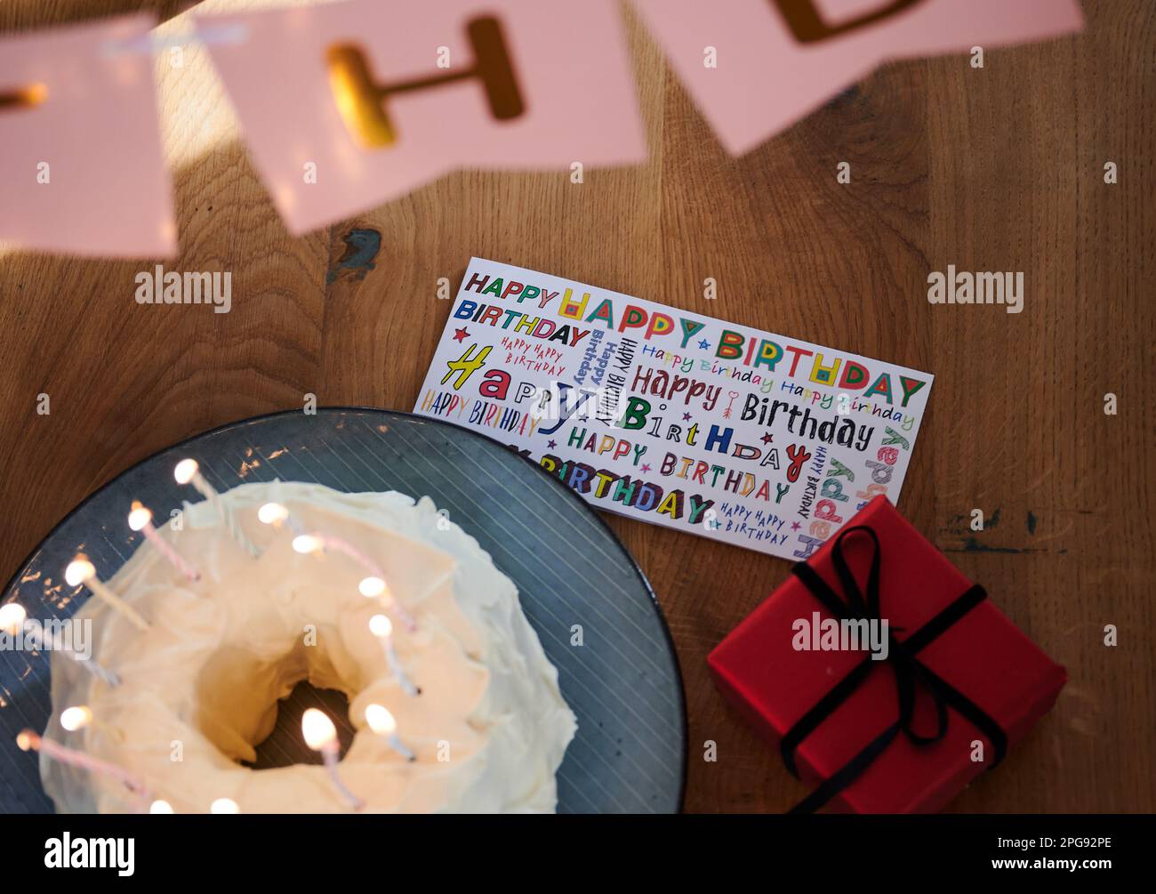 Berlin, Allemagne. 19th mars 2023. « Joyeux anniversaire » est écrit dans de nombreuses polices sur une carte placée sur une table d'anniversaire à côté d'un gâteau aux bougies allumées. Credit: Annette Riedl/dpa/Alay Live News Banque D'Images