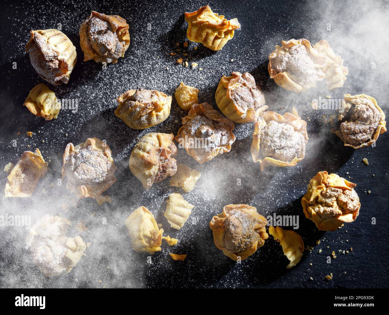 Mini-tartes de noix jaunes saupoudrées de sucre en poudre sur fond de pierre anthracite gris foncé Banque D'Images
