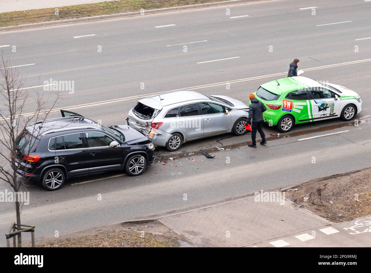 Riga, Lettonie - 15 février 2023: Accident de voiture avec trois voitures dans une rue de ville. Un conducteur se trouve à proximité de voitures épaves et remplit les documents d'assurance. Banque D'Images