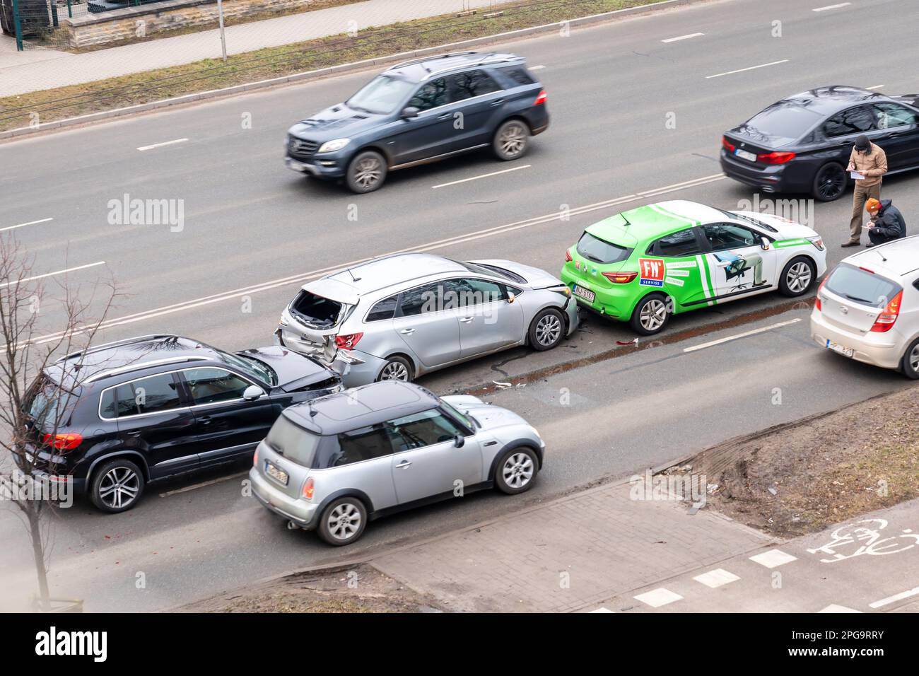 Riga, Lettonie - 15 février 2023: Accident de voiture avec trois voitures dans une rue de ville. Un conducteur se trouve à proximité de voitures épaves et remplit les documents d'assurance. Banque D'Images