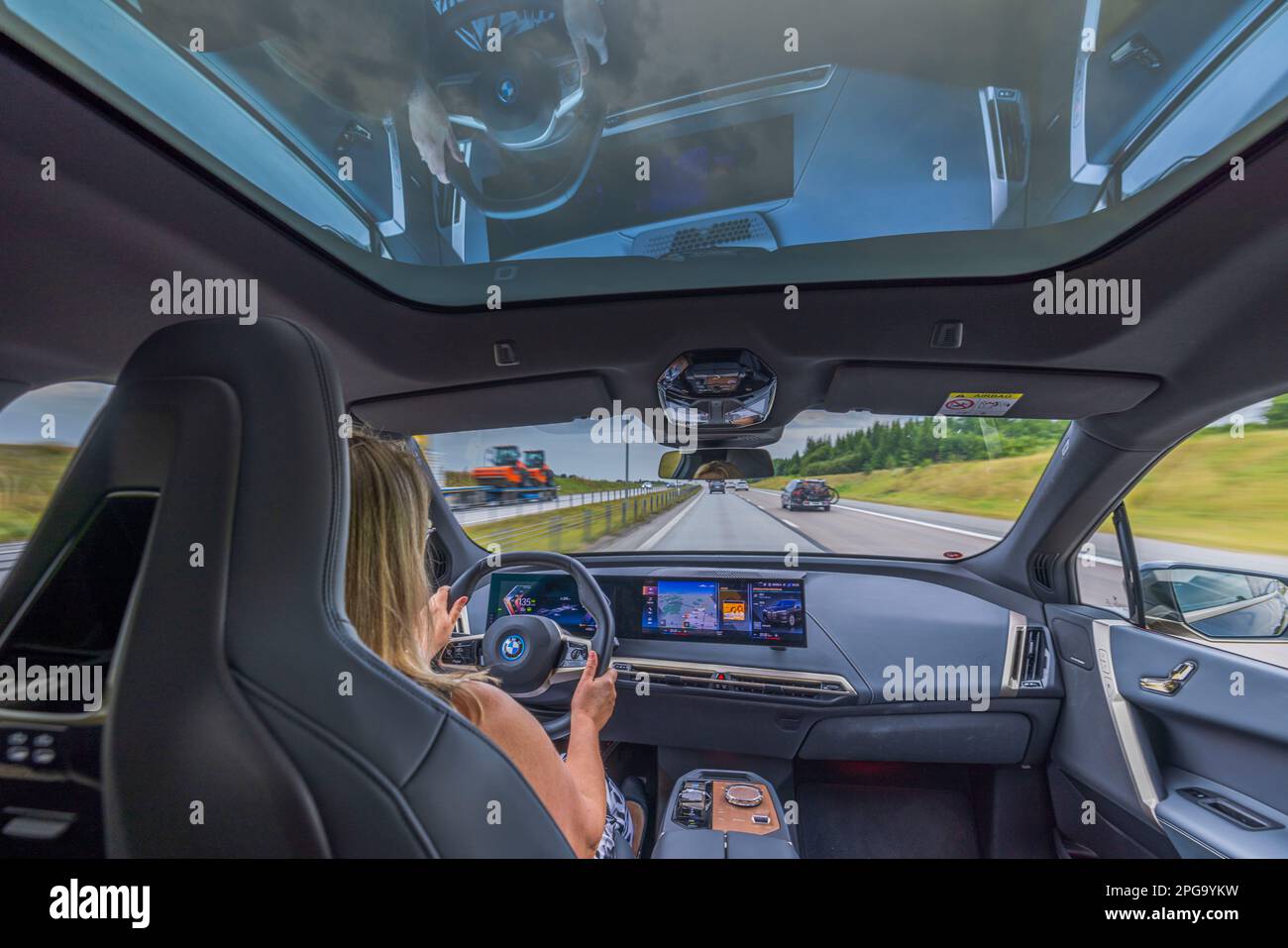 Belle vue intérieure de la BMW iX 40 sur la route. Une femme conduit un véhicule sur la voie publique. Suède. Uppsala. Banque D'Images