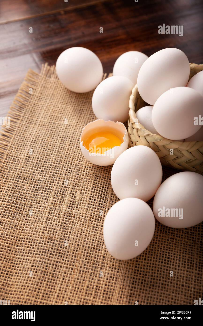Nombreux œufs de poulet blanc et jaune sur une table rustique en bois. Produit alimentaire nutritif et économique très populaire. Banque D'Images